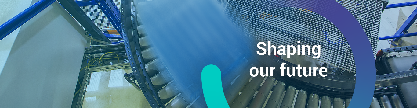 The words, 'Shaping our Future' inside a circle graphic overlayed on top of an image of a moving pallet on a conveyor belt