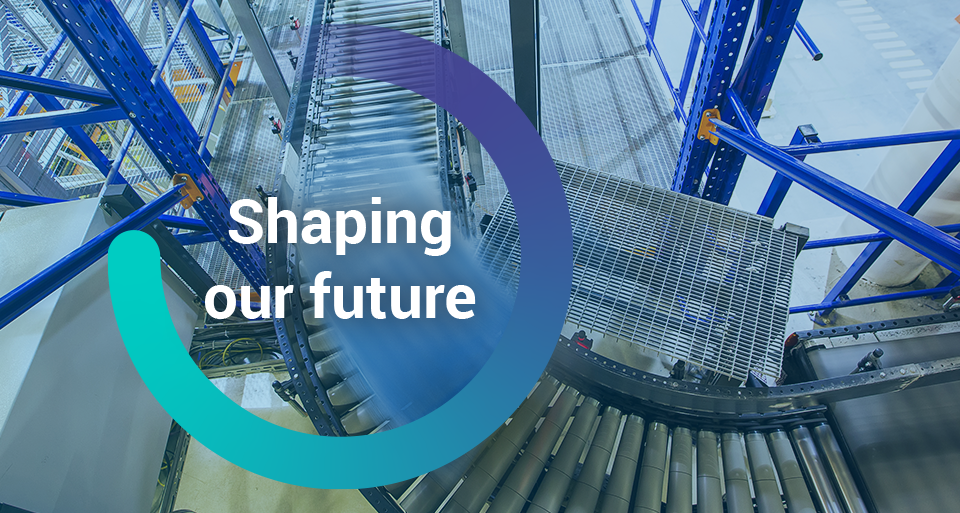 The words, 'Shaping our Future' inside a circle graphic overlayed on top of an image of a moving pallet on a conveyor belt