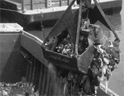 A black and white photograph of a digger claw collecting waste